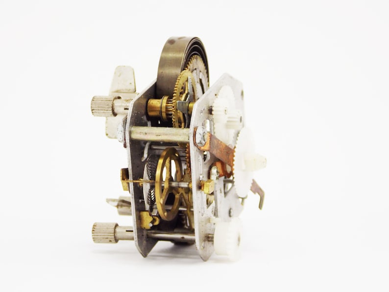 May include: Close-up of a disassembled clock mechanism with gears, springs, and metal parts.