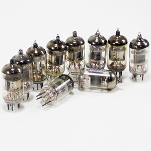 May include: A group of ten vintage vacuum tubes with glass enclosures and metal bases. The tubes are arranged in a semi-circle on a white surface.
