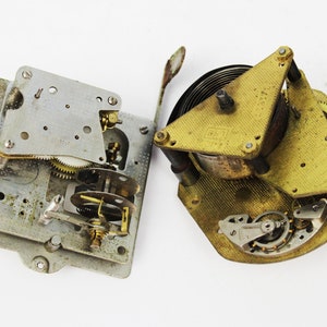 Peut inclure: Deux mécanismes d'horloge démontés, l'un avec une base argentée et l'autre avec une base en laiton. Les deux mécanismes ont des engrenages et des ressorts complexes.