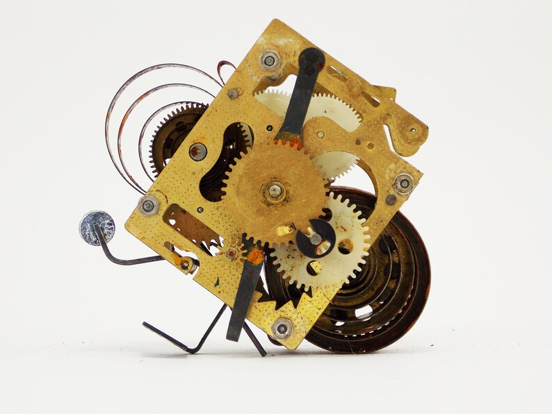May include: A close-up of a vintage clockwork mechanism with intricate gears and a spring. The mechanism is made of brass and has a worn, aged appearance.