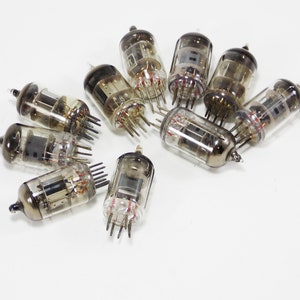 May include: A group of ten vintage vacuum tubes, with a clear glass body and metal base, arranged in a circle on a white surface.