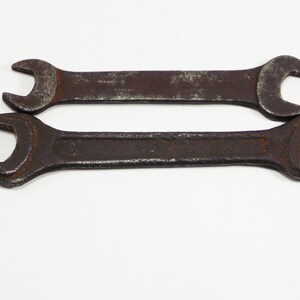 Peut inclure: Deux clés à molette rouillées, l'une sur l'autre, sur un fond blanc.