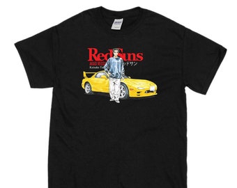May include: Black t-shirt featuring a graphic of a yellow car and a person standing next to it. The text "Red Suns" is printed in red above the graphic. The text "AKAGI REDSUNS" and "Keisuke Takahashi" are printed in black below the graphic.
