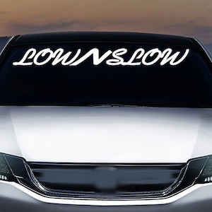 May include: A silver car with the words "LOWNSLOW" written in white on the windscreen.