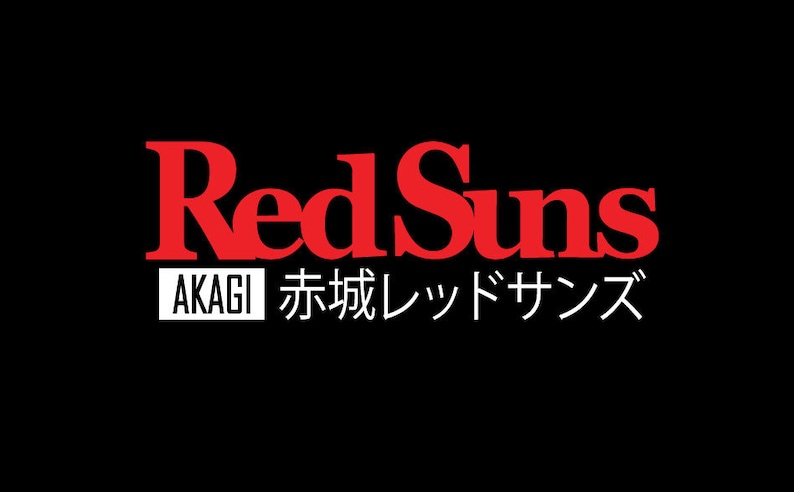 Pu&ograve; includere: Un design grafico su sfondo nero che presenta il testo RedSuns in lettere rosse in grassetto. Sotto, un rettangolo bianco contiene la parola AKAGI in nero, seguita dal testo giapponese 赤城レッドサンズ in lettere bianche.