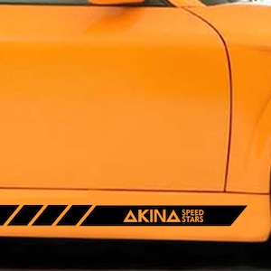 May include: Orange car with a black racing stripe and the words "AKINA SPEED STARS" on the side.