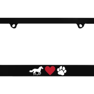 May include: Black license plate frame with a white horse silhouette, a red heart, and a white paw print. The frame has a rectangular shape with rounded corners and mounting holes.