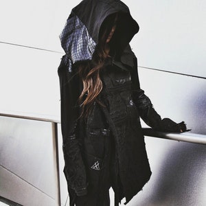 May include: A black hooded jacket with a textured detail on the hood. The jacket has a long, flowing design and is made of a soft, comfortable fabric.