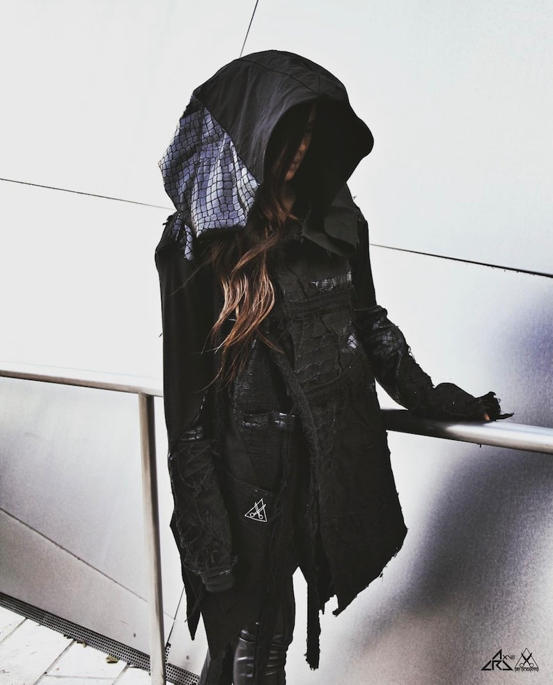 May include: A black hooded jacket with a textured detail on the hood. The jacket has a long, flowing design and is made of a soft, comfortable fabric.