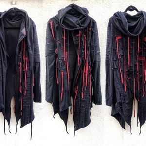 May include: Black hooded jacket with long red fabric strips hanging from the seams. The jacket has a distressed look with several rips and tears.