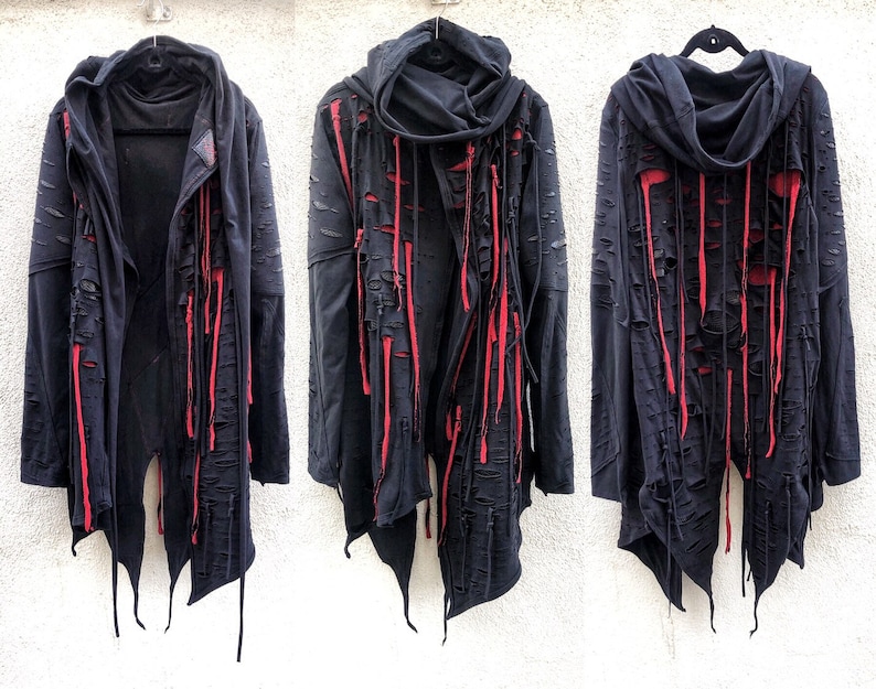 May include: Black hooded jacket with long red fabric strips hanging from the seams. The jacket has a distressed look with several rips and tears.