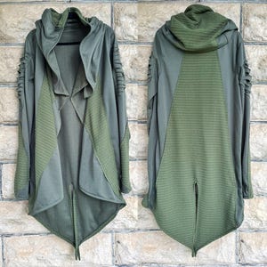 May include: An olive green hooded cardigan featuring a draped open front, long sleeves with shredded cut-out detailing, and a textured ribbed knit panel on the back and front sides. The garment has a high-low hemline with a central back slit.