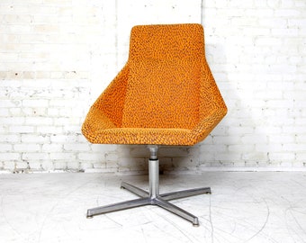 May include: A swivel chair with a star-shaped base and orange patterned upholstery.