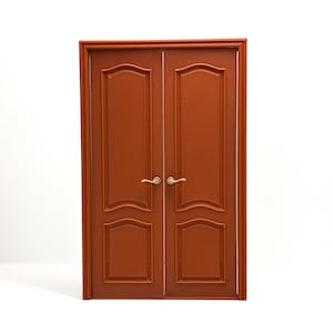 May include: A set of double doors in a reddish-brown finish, featuring two rectangular panels on each door with arched tops. The doors are framed by a matching border and include two small, curved, gold-colored metal handles at the center.