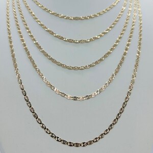 May include: A set of six gold chains with a diamond-cut design. The chains are layered on a white mannequin bust.