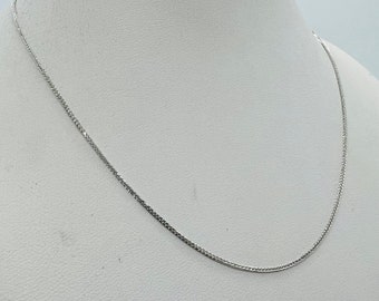 May include: A silver chain necklace on a white mannequin bust.