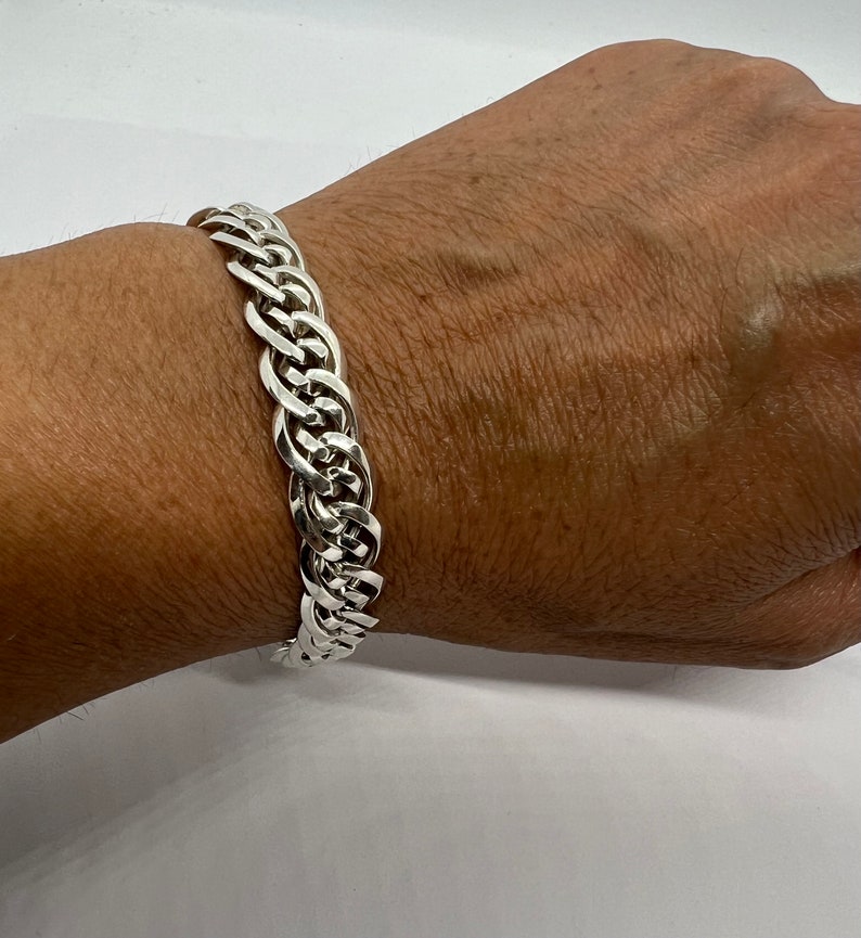 Op de afbeelding: Een zilveren armband met een gevlochten ontwerp.