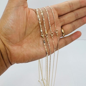 May include: Four gold-coloured necklaces with various chain styles are shown. The chains include a mariner link, a rope chain, and a box chain. Each necklace has a clasp. The necklaces are presented against a light background.