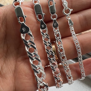 May include: Four silver chain necklaces of varying widths and lengths. The chains are all made of a classic curb link style.