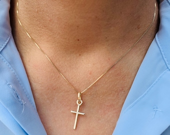 May include: A gold chain necklace with a small gold cross pendant.