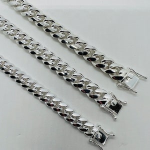 May include: Three silver curb chain necklaces of varying lengths. The chains are made of thick, interlocking links.