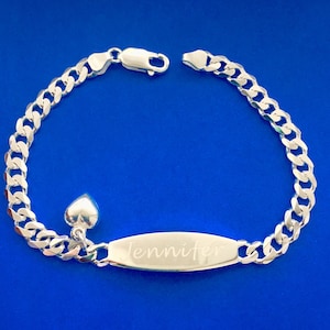 May include: A silver curb chain bracelet with a heart charm and a rectangular tag engraved with the name "Jennifer".