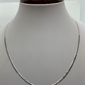 May include: A silver chain necklace on a white mannequin bust.
