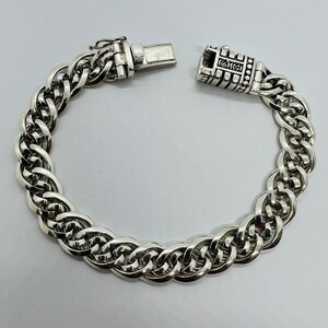 Op de afbeelding: Een zilveren kettingarmband met een gedetailleerde sluiting. De ketting is gemaakt van meerdere verweven schakels.