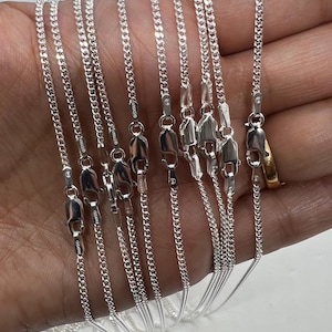 May include: A collection of silver chain necklaces of varying lengths. The chains are all the same style, with a delicate, curb link design.