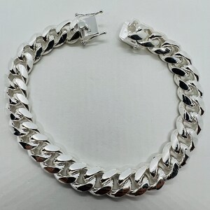 May include: A silver curb chain bracelet with a lobster clasp closure.