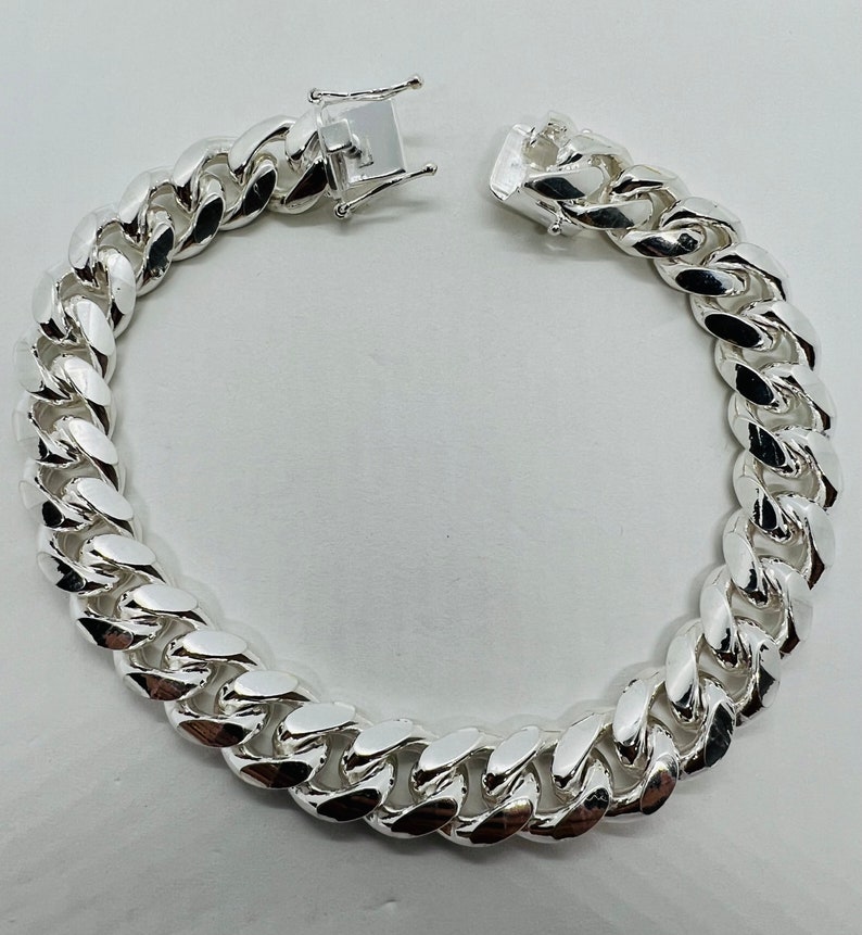 May include: A silver curb chain bracelet with a lobster clasp closure.