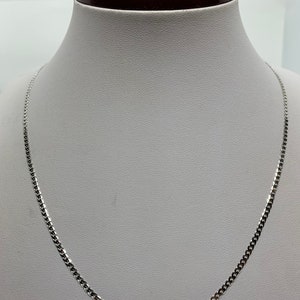 May include: A silver chain necklace with a curb link style. The chain is on a white mannequin bust.