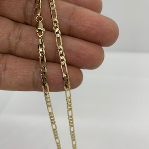 May include: A gold chain necklace with a classic figaro design. The chain is made of solid gold and has a polished finish.