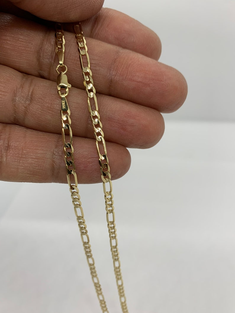 May include: A gold chain necklace with a classic figaro design. The chain is made of solid gold and has a polished finish.