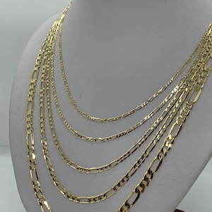 May include: A set of six gold chain necklaces of varying widths, displayed on a white mannequin bust. The chains are all made of a classic figaro design.