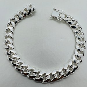 May include: A silver curb chain bracelet with a lobster clasp closure.