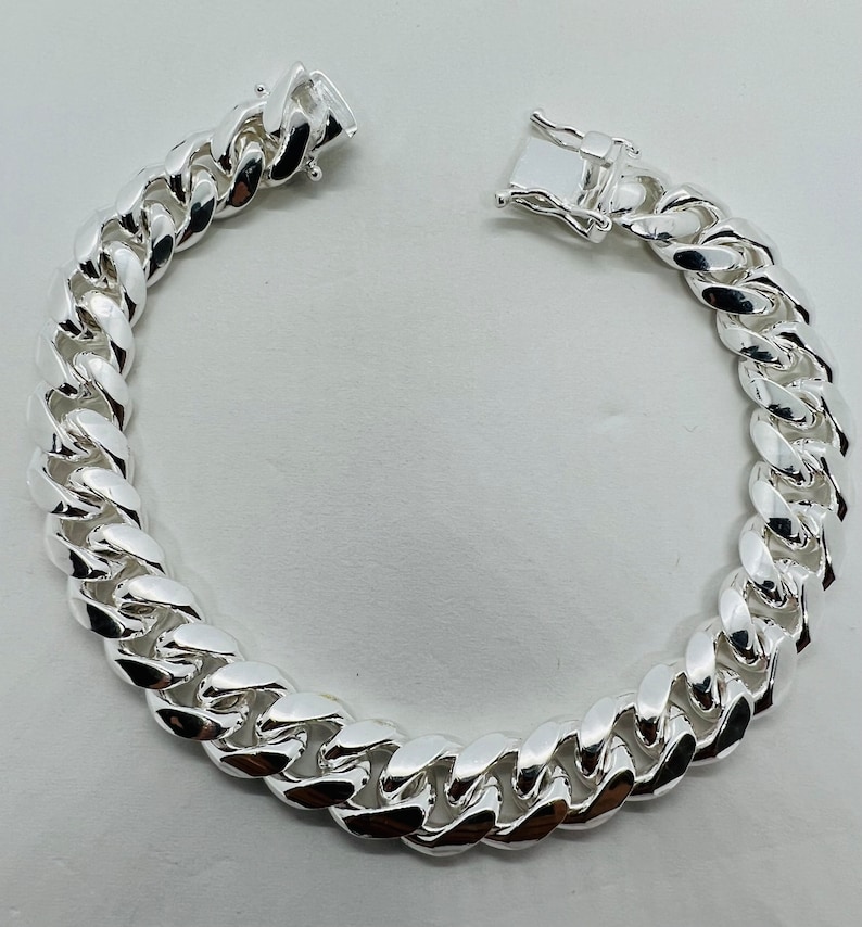 May include: A silver curb chain bracelet with a lobster clasp closure.