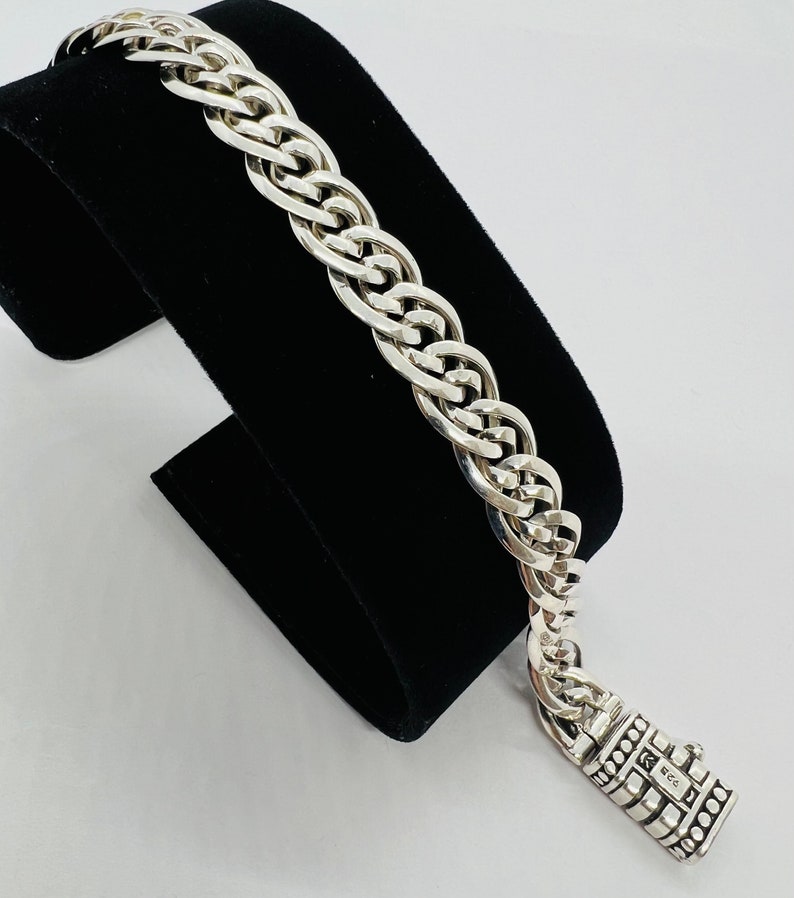 Op de afbeelding: Een zilveren armband met een gevlochten ketting en een zilveren sluiting. De sluiting heeft een kleine inscriptie "925".