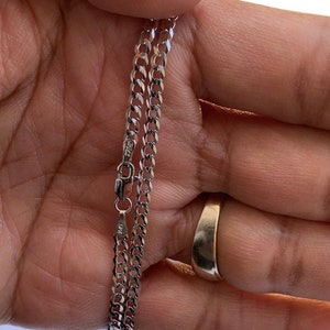 May include: A silver curb chain necklace with a lobster clasp. The chain is about 20 inches long.
