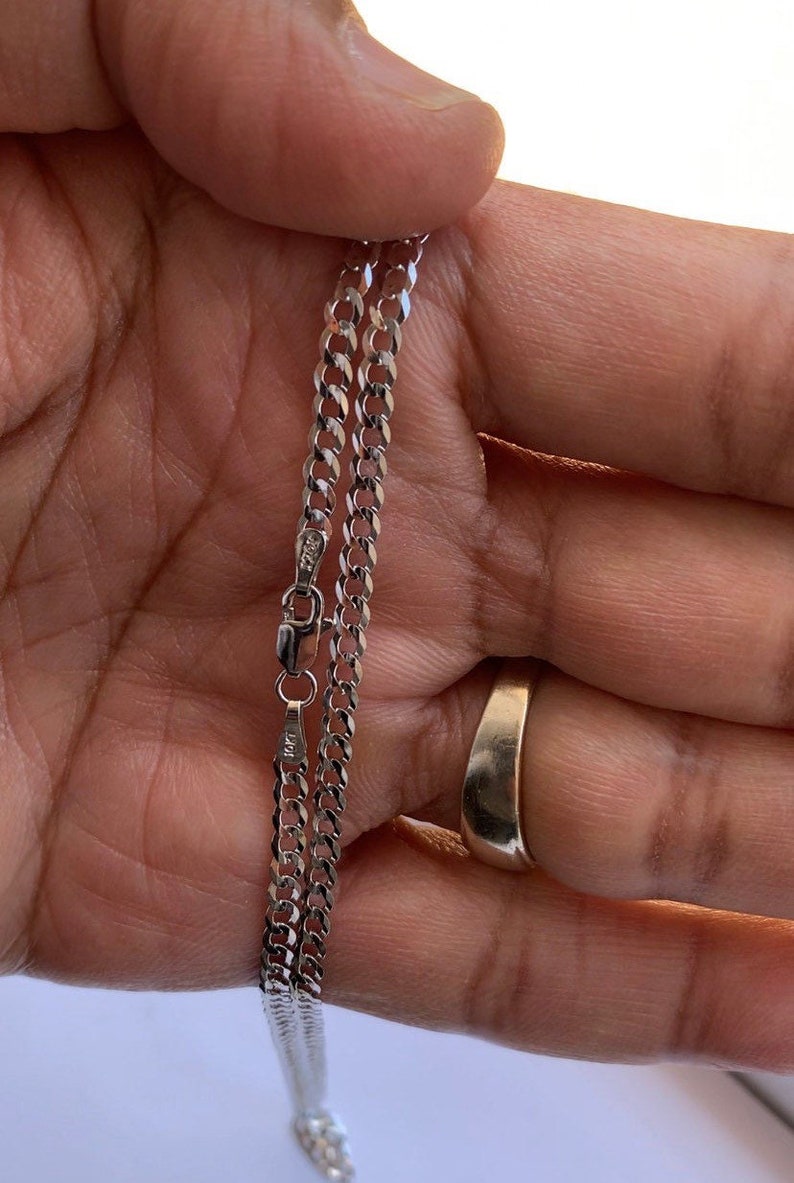 May include: A silver curb chain necklace with a lobster clasp. The chain is about 20 inches long.