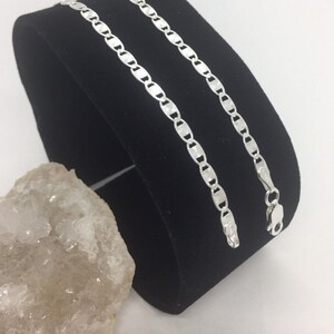 May include: A silver mariner chain necklace with a shiny finish. The chain is displayed on a black velvet stand.