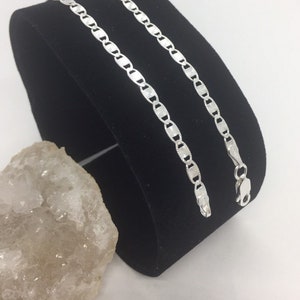 May include: A silver chain necklace with a mariner link design. The chain is displayed on a black velvet background.