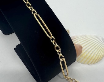 May include: A gold chain bracelet with a unique link design. The bracelet features alternating oval and round links.