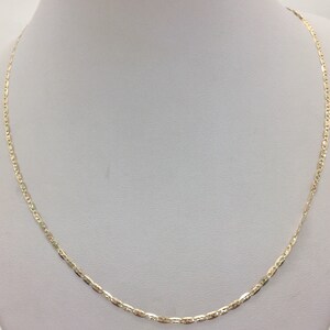 May include: A gold chain necklace with a delicate, patterned design. The chain is on a white display stand.