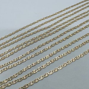 May include: A set of eight gold-toned chains with a diamond-shaped pattern. The chains are arranged in a staggered pattern, with the longest chain at the top and the shortest chain at the bottom.