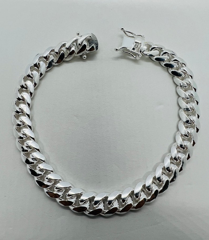 May include: A silver curb chain bracelet with a lobster clasp closure.