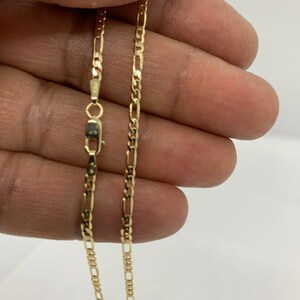 May include: A gold chain necklace with a classic figaro design. The chain is approximately 20 inches long and has a lobster claw clasp.
