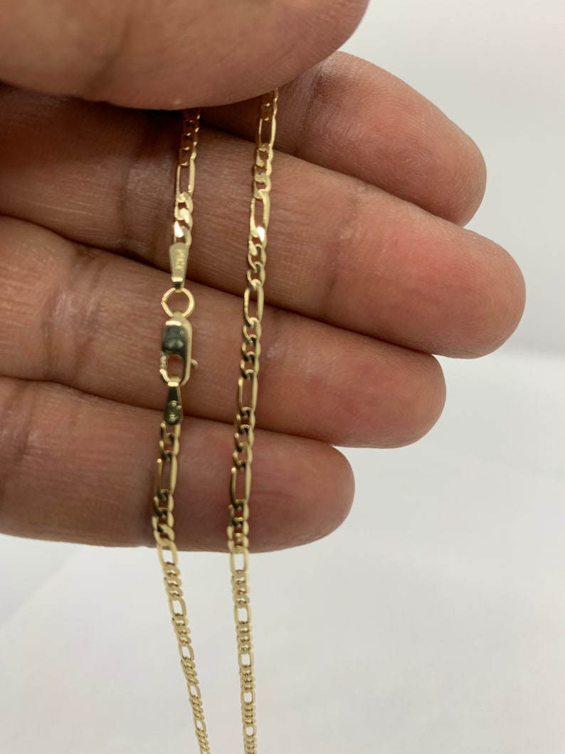 May include: A gold chain necklace with a classic figaro design. The chain is approximately 20 inches long and has a lobster claw clasp.