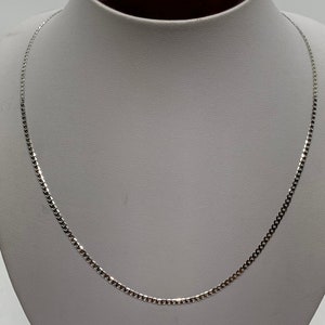 May include: A silver chain necklace with a box chain design. The chain is on a white mannequin.