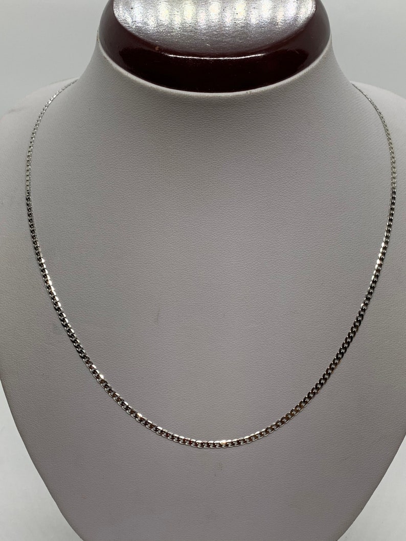 May include: A silver chain necklace with a box chain design. The chain is on a white mannequin.
